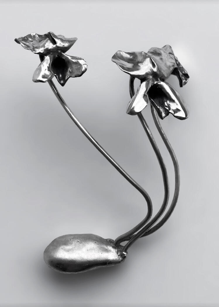 A handcrafted cast silver piece of jewelry sits against a white background. There are three wild blue violets coming off of a tuber all direct cast in silver. Made by Mia Donalson.